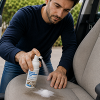 Application d’un détachant shampouineuse sur un siège de voiture en tissu, avec le produit pulvérisé directement sur une tache pour faciliter son nettoyage